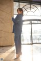 A woman in a blue suit standing in front of a window.