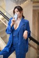 A woman in a blue suit holding a cell phone.