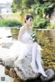 A woman sitting on a rock holding a bouquet of flowers.