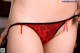 A close up of a woman wearing a red thong.