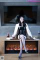 A woman sitting on top of a fireplace next to a television.