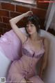 A woman in a pink lingerie sitting in a bathtub.