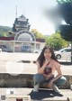 A woman sitting on the curb in front of a building.