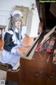 A woman in a maid outfit playing a piano.