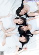 A group of young women laying on top of a bed.