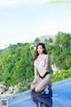 A woman in a white and black bathing suit sitting on the edge of a pool.