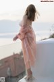 A woman in a pink dress standing on a balcony.