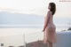 A woman in a pink dress standing on a balcony.