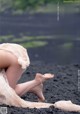 A woman in a white dress sitting on a black sand beach.