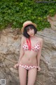 A woman in a bikini and straw hat posing for a picture.