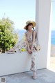 A woman wearing a straw hat sitting on a wall.