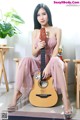 A woman sitting on a chair holding a guitar.