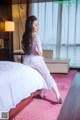 A woman sitting on a bed in a hotel room.