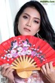 A woman holding a red fan with flowers on it.