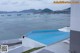 A woman laying on the edge of a swimming pool next to a beach.