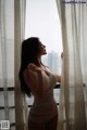 A woman in a white lingerie looking out a window.