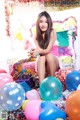 A woman sitting on top of a pile of balloons.