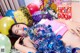 A woman laying on top of a pile of presents and balloons.