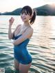 A woman in a blue bathing suit standing in the water.