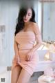 A woman in a pink dress sitting on a bathroom counter.