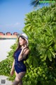 A woman in a blue swimsuit and a white hat posing for a picture.