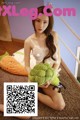 A woman sitting on the floor holding a stuffed broccoli.