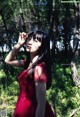 A woman in a red dress standing in the woods.