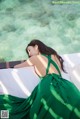 A woman in a green dress laying on a bed.