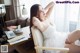 A woman in a white dress sitting on a chair.