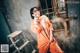 A woman in an orange jumpsuit posing for a picture.