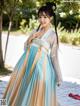 A woman in a blue and beige hanbok is posing for a picture.