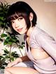 A woman sitting on top of a white chair next to a plant.