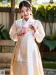 A woman in a white and orange hanbok is posing for a picture.