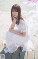 A woman in a white dress sitting on a wooden dock.