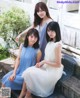 A group of three young women sitting on a bench.