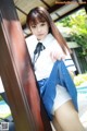 A woman in a school uniform leaning against a wall.