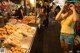 A woman standing in front of a food stand at night.