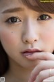 A close up of a woman's face with her hand on her chin.