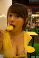 A woman in a yellow shirt eating a piece of food.