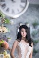 A woman in a wedding dress standing in front of a clock.