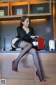 A woman sitting on top of a counter next to a coffee machine.